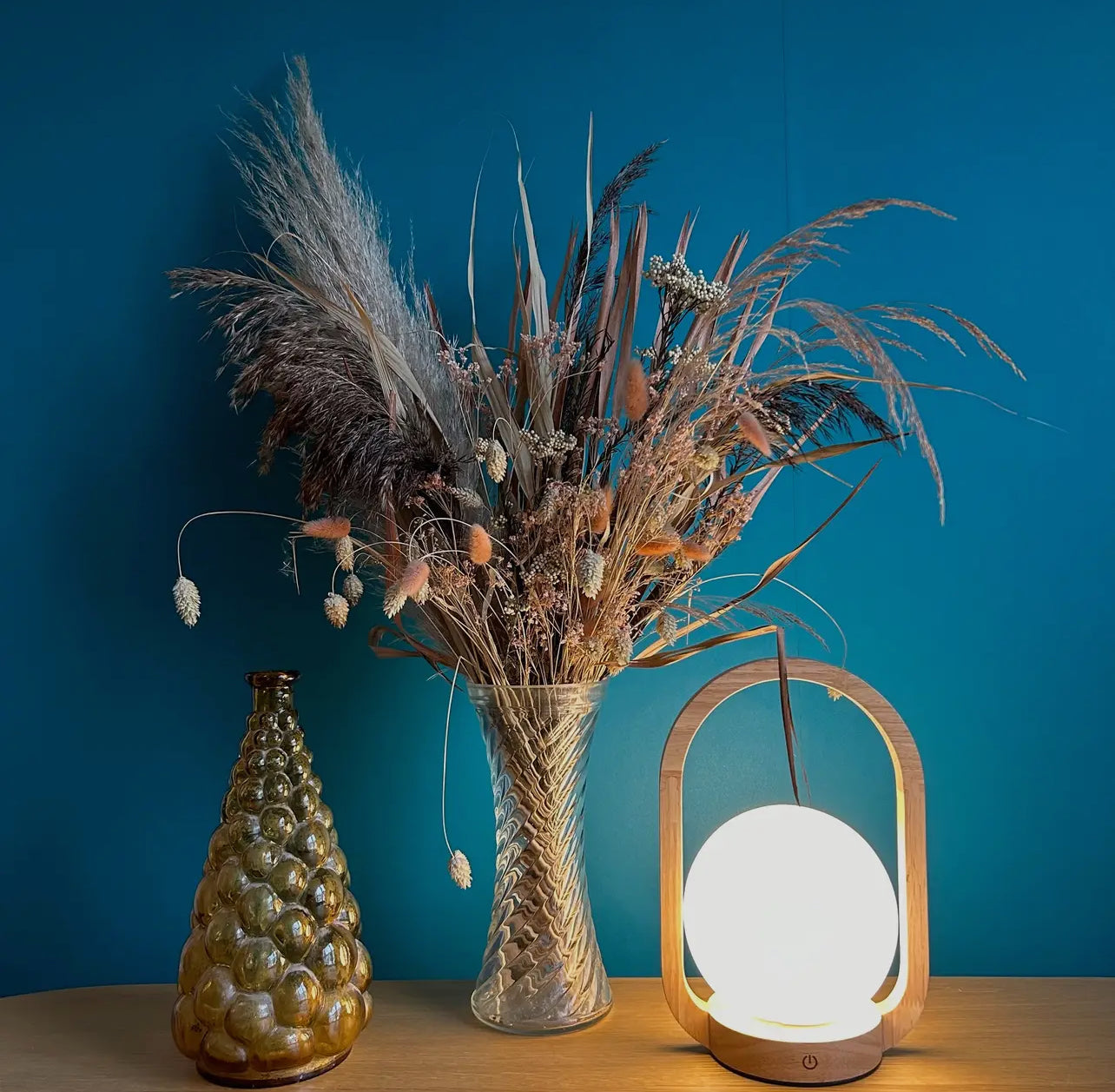 Beech Lantern Rechargeable Touch Lamp from Happybara’s Home Decor and Accessories collection in front of a blue wall.